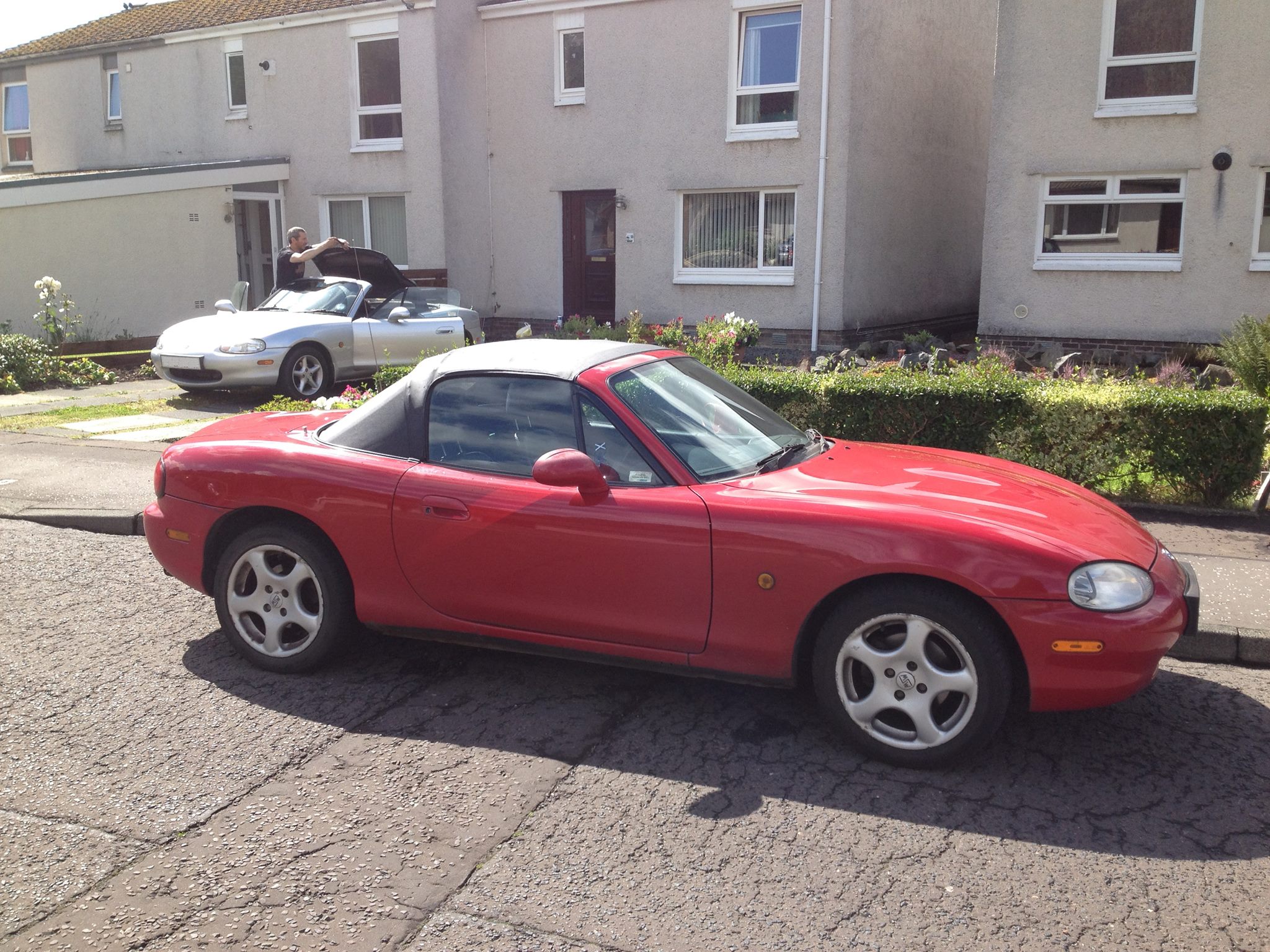 Two Mazda MX5 MK1s outside the garage